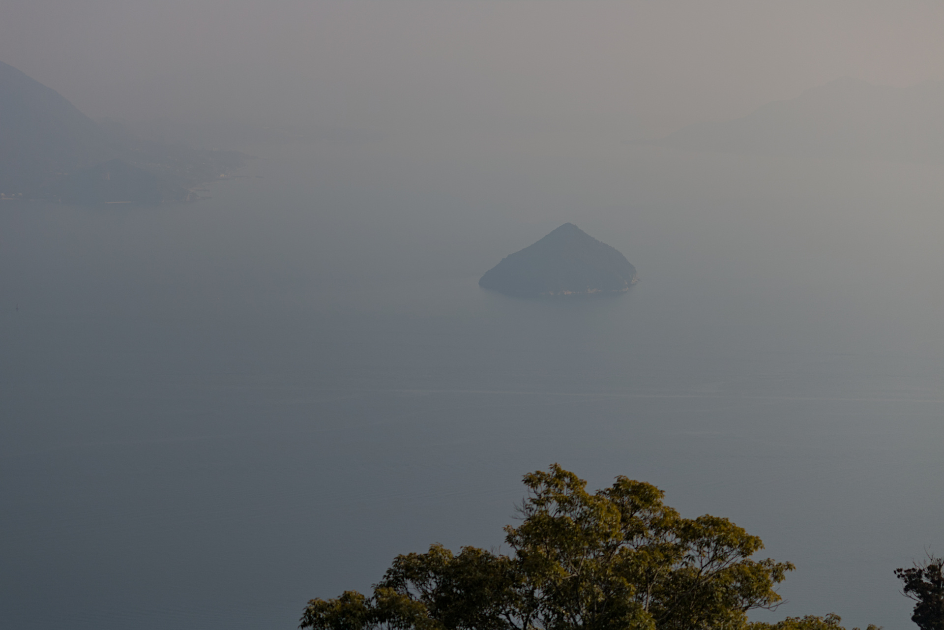 Foggy view from above of the sea and a lone island in the distance.